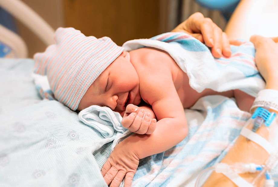 Świeżo upieczona mama trzymająca noworodka na brzuchu