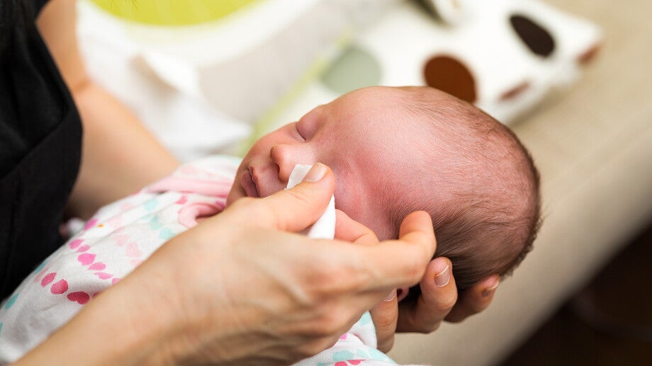 Wieczorna pielęgnacja noworodka – mama przemywa oczy dziecku