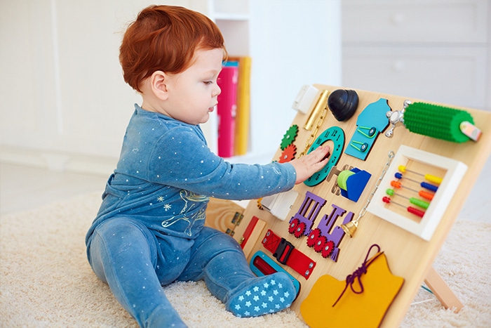 Dziewczynka bawiąca się tablicą manipulacyjną Montessori