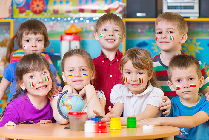 Edukacja wielokulturowa – uśmiechnięte przedszkolaki z flagami krajów namalowanymi na buziach
