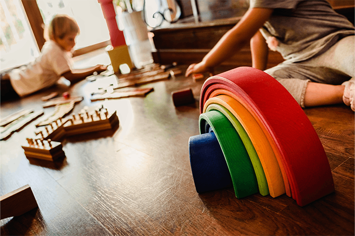 Tęcza Montessori i cylindry Montessori leżące na podłodze podczas zabawy dzieci