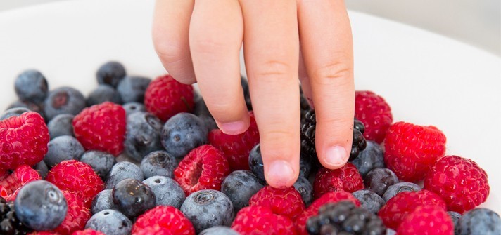 Baby having blueberries and raspberries as a snack