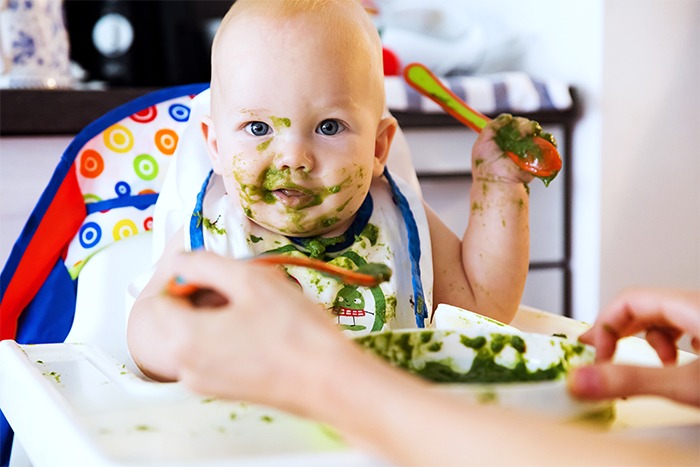 child eating green soup
