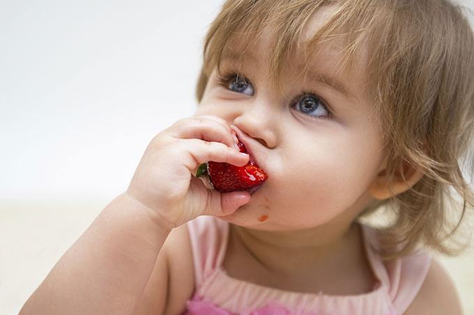 the girl is eating a strawberry