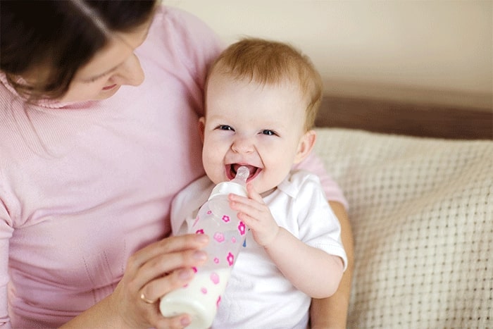 mom is feeding the baby with a  bottle