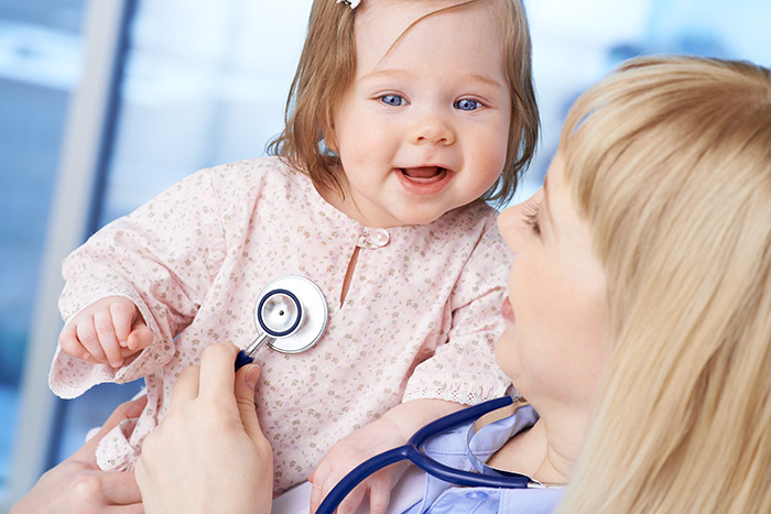 the pediatrician is examining the smiling little girl