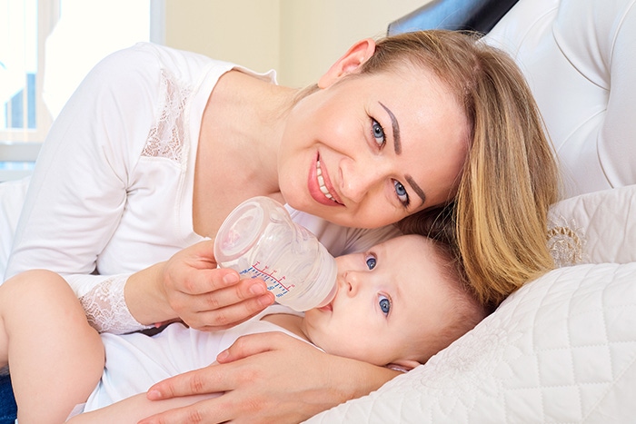 woman feeding baby milk from bottle 