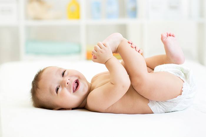Uśmiechnięte niemowlę bawi się stopą