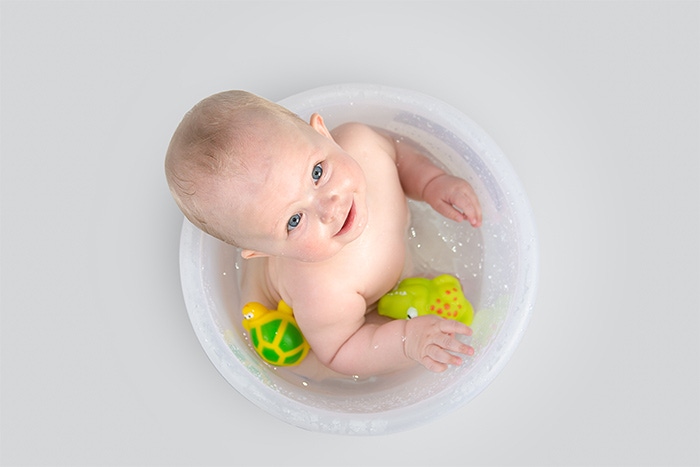 smiling baby in a bath bucket