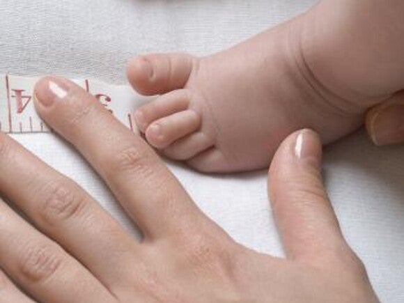 mother measures the foot of the baby