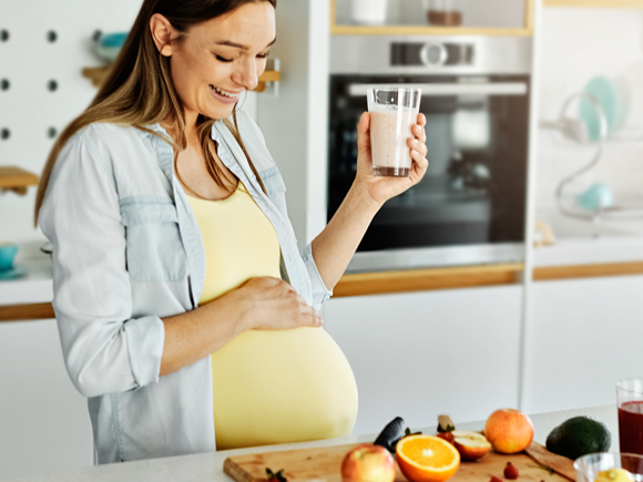 Kobieta w ciąży ze szklanką soku w kuchni