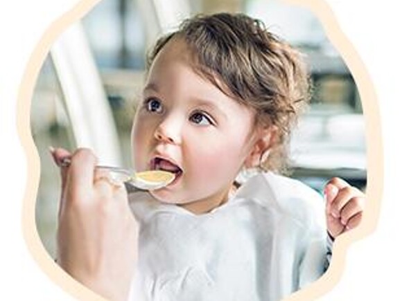 Uśmiechnięte dziecko jedzące kaszkę mleczną