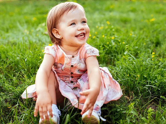 Mała dziewczynka siedzi na zielonym trawniku 