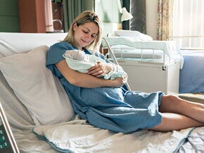 Świeżo upieczona mama po cesarskim cięciu trzyma w objęciach noworodka
