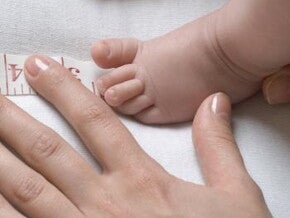 mother measures the foot of the baby