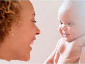 Uśmiechnięta mama patrzy w oczy niemowlęciu