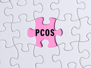 Zespół policystycznych jajników: czarny napis PCOS na różowym tle obok białych puzzli 