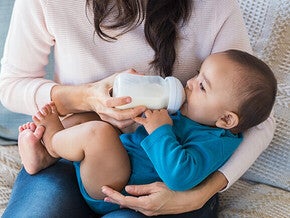 Feeding a baby with a bottle on a lap.