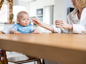 Feeding baby at kitchen table, morning light.