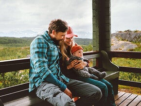 Family cuddling on a porch with scenic mountain backdrop.