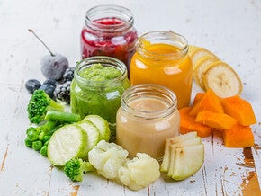 Colorful fruit and vegetable purees in jars with fresh produce nearby.