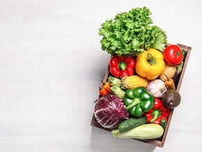 Basket of assorted fresh vegetables on a light background.