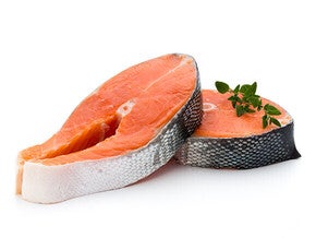 Two raw salmon steaks with herbs on top.