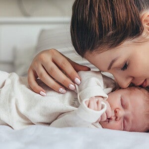 Świeżo upieczona mama po cesarskim cięciu leży na łóżku z noworodkiem