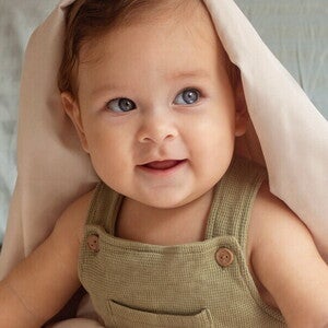 Siedzący niemowlak okryty kołdrą