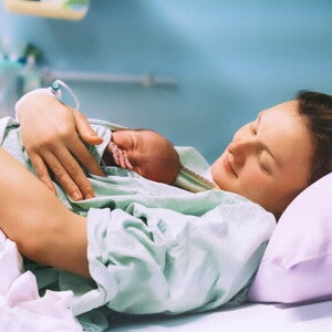 Poród lotosowy: mama obejmująca swoje nowo narodzone dziecko Poród lotosowy: mama obejmująca swoje nowo narodzone dziecko