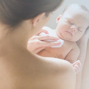 Sposoby na lepszy sen – mama trzyma na kolanach śpiące niemowlę