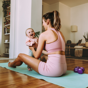 Szczęśliwa mama ćwiczy z dzieckiem na macie do ćwiczeń w domu
