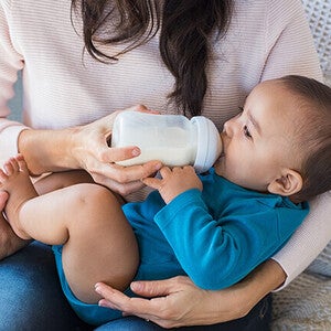 Feeding a baby with a bottle on a lap.