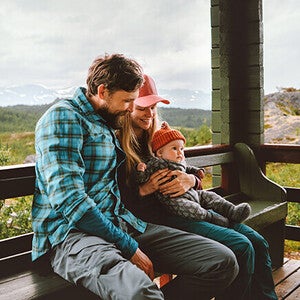 Family cuddling on a porch with scenic mountain backdrop.