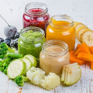 Colorful fruit and vegetable purees in jars with fresh produce nearby.