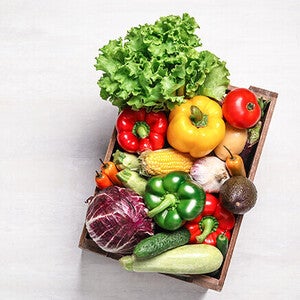 Basket of assorted fresh vegetables on a light background.
