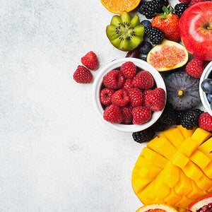 Assorted fruits including berries, kiwi, and mango on a light surface.