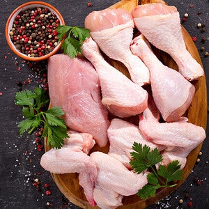 Raw chicken drumsticks with herbs and peppercorns on wooden board