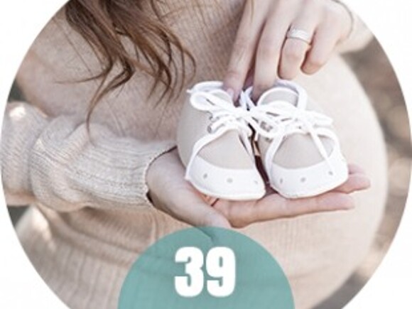 Kobieta w 39 tygodniu ciąży z małymi bucikami