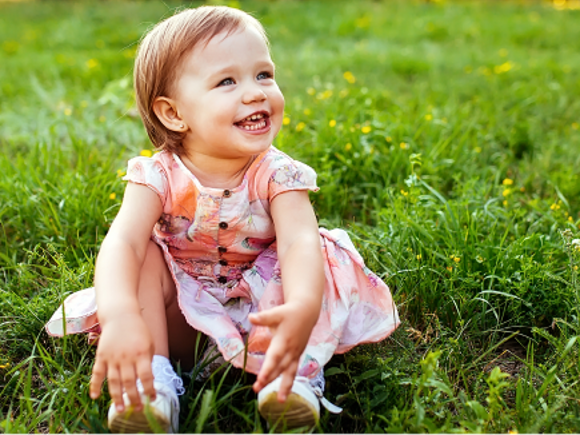 Mała dziewczynka siedzi na zielonym trawniku 
