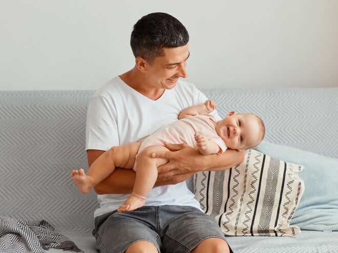 Mama podtrzymuje płaczącego chłopca, który stoi na kanapie.