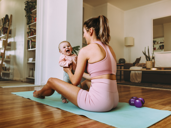 Szczęśliwa mama ćwiczy z dzieckiem na macie do ćwiczeń w domu