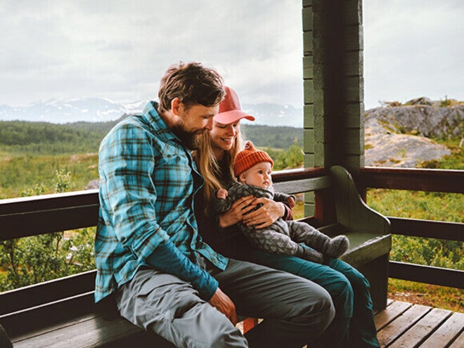 Family cuddling on a porch with scenic mountain backdrop.