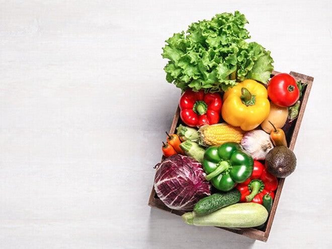Basket of assorted fresh vegetables on a light background.