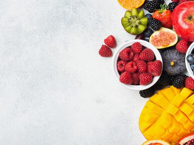 Assorted fruits including berries, kiwi, and mango on a light surface.