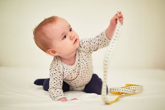 niemowle trzymajace centymetr krawiecki