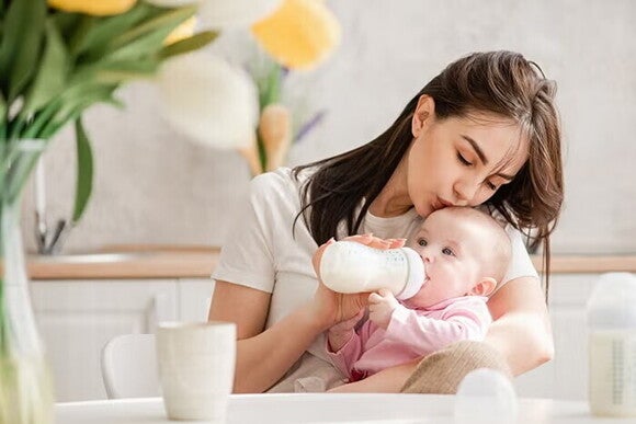 Mama karmi dziecko mlekiem z butelki Mama karmi dziecko mlekiem z butelki