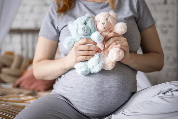 Ciąża bliźniacza kobieta obrazująca bliźniaki dwoma misiami – różowym i niebieskim Ciąża bliźniacza kobieta obrazująca bliźniaki dwoma misiami – różowym i niebieskim