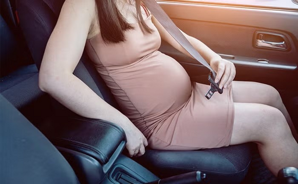 Podróż samochodem w ciąży – kobieta zapinająca pas bezpieczeństwa Podróż samochodem w ciąży – kobieta zapinająca pas bezpieczeństwa