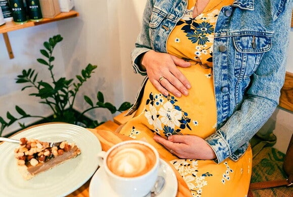 Ochota na słodycze w ciąży – kobieta w ciąży z ciastkiem i słodką kawą